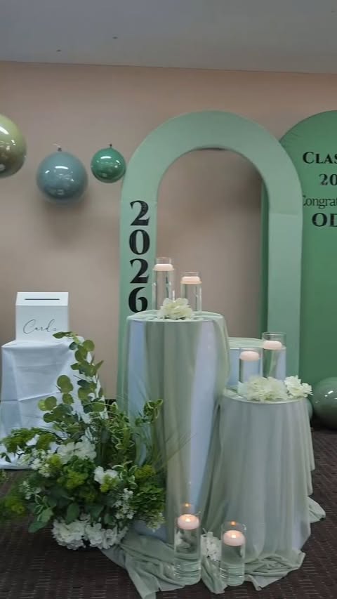 Storefront-scale sage arch with cocktail tables and candles